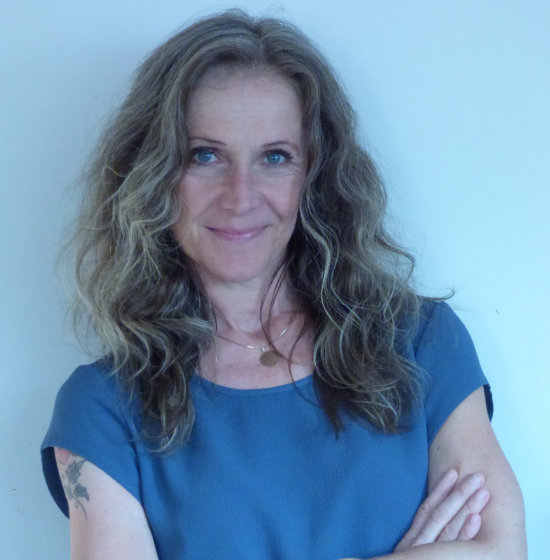 Melanie Rienzner, fotografiert von der Seite auf einem Baumstamm sitzend